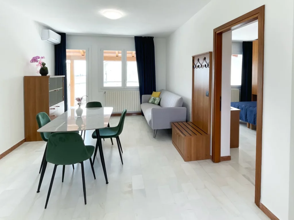 Soggiorno con divano letto tv climatizzatore tavolo da pranzo e cucina attrezzata - Appartamento ad Aviano vicino al Cro e alla Base Aerea di Aviano. Smart Residence Aviano